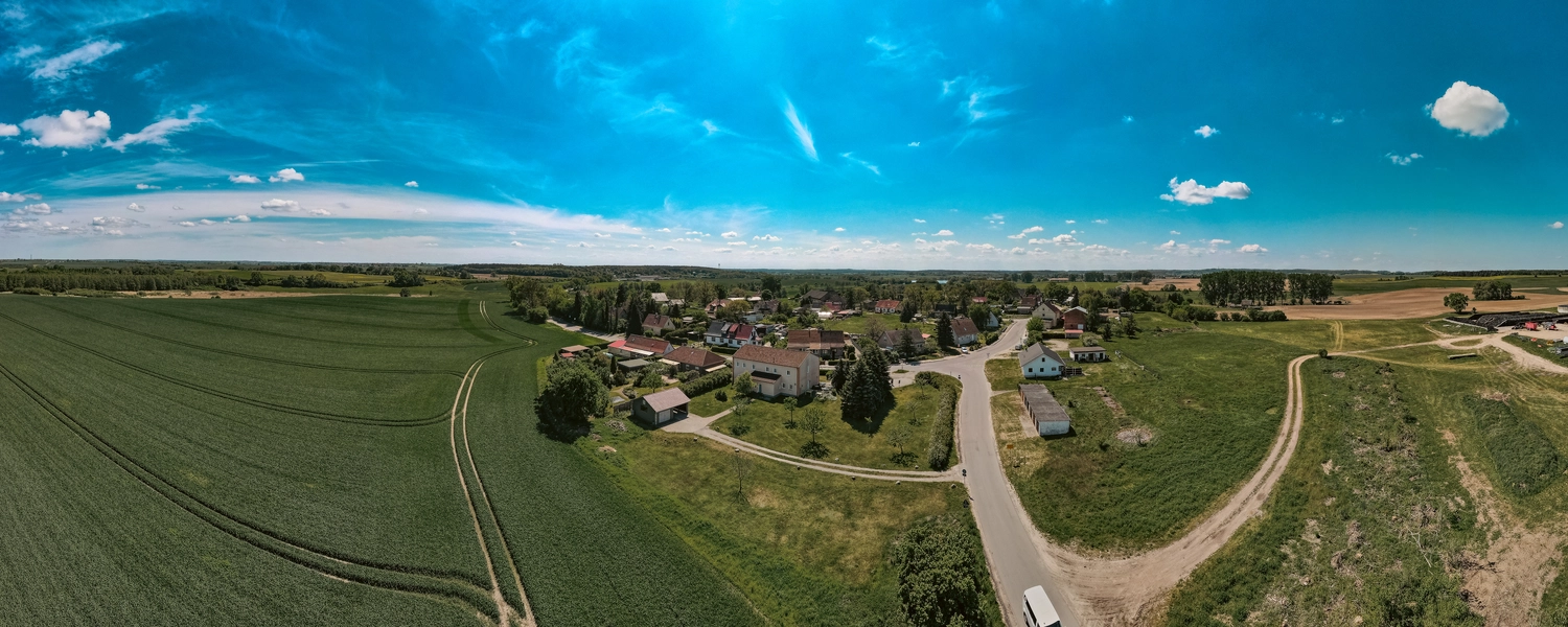 Erbkrug Blankensee -  Ferienapartments - Ein Luftpanorama eines ländlichen Dorfes, eingebettet zwischen weitläufigen landwirtschaftlichen Feldern unter einem strahlend blauen Himmel mit vereinzelten Wolken.